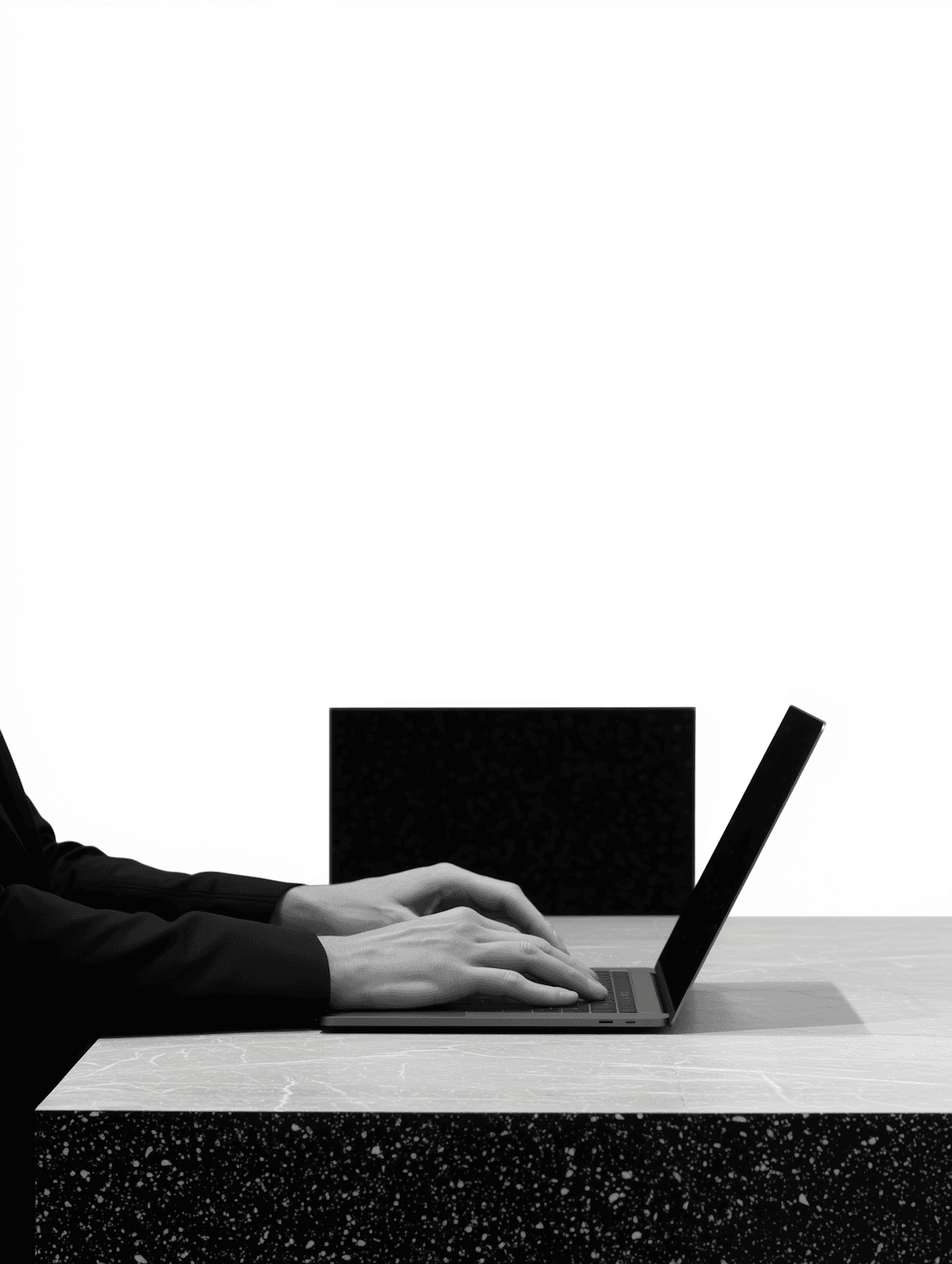 Hands resting on a laptop keyboard at a stone desk